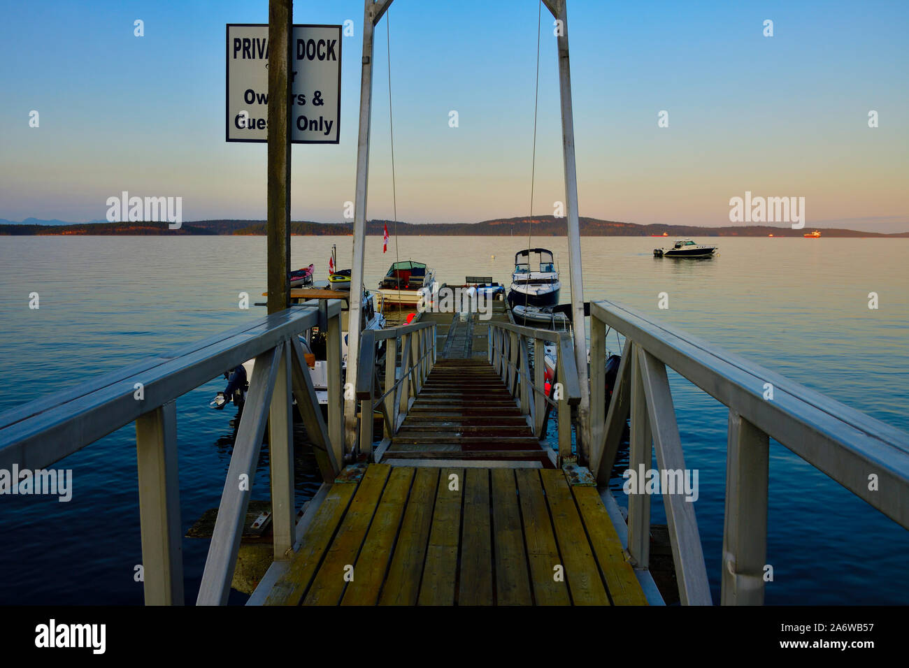 Eine Bootsanlegestelle ragt heraus in die Stewart Kanal mit Sportbooten auf einen ruhigen Sommer Abend auf Vancouver Island, British Columbia Kanada geladen. Stockfoto
