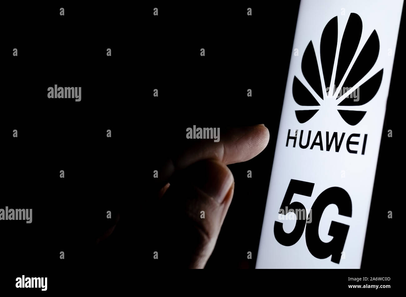 Huawei 5G Logo auf einem Bildschirm des Smartphones in einem dunklen Raum und einen Finger zu berühren. Stockfoto