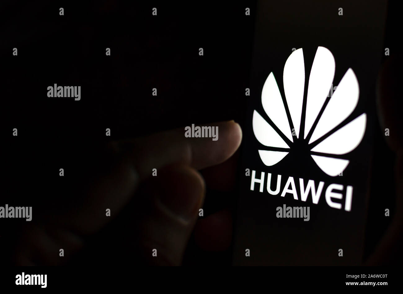 Huawei Logo auf einem Bildschirm des Smartphones in einem dunklen Raum und einen Finger zu berühren. Stockfoto