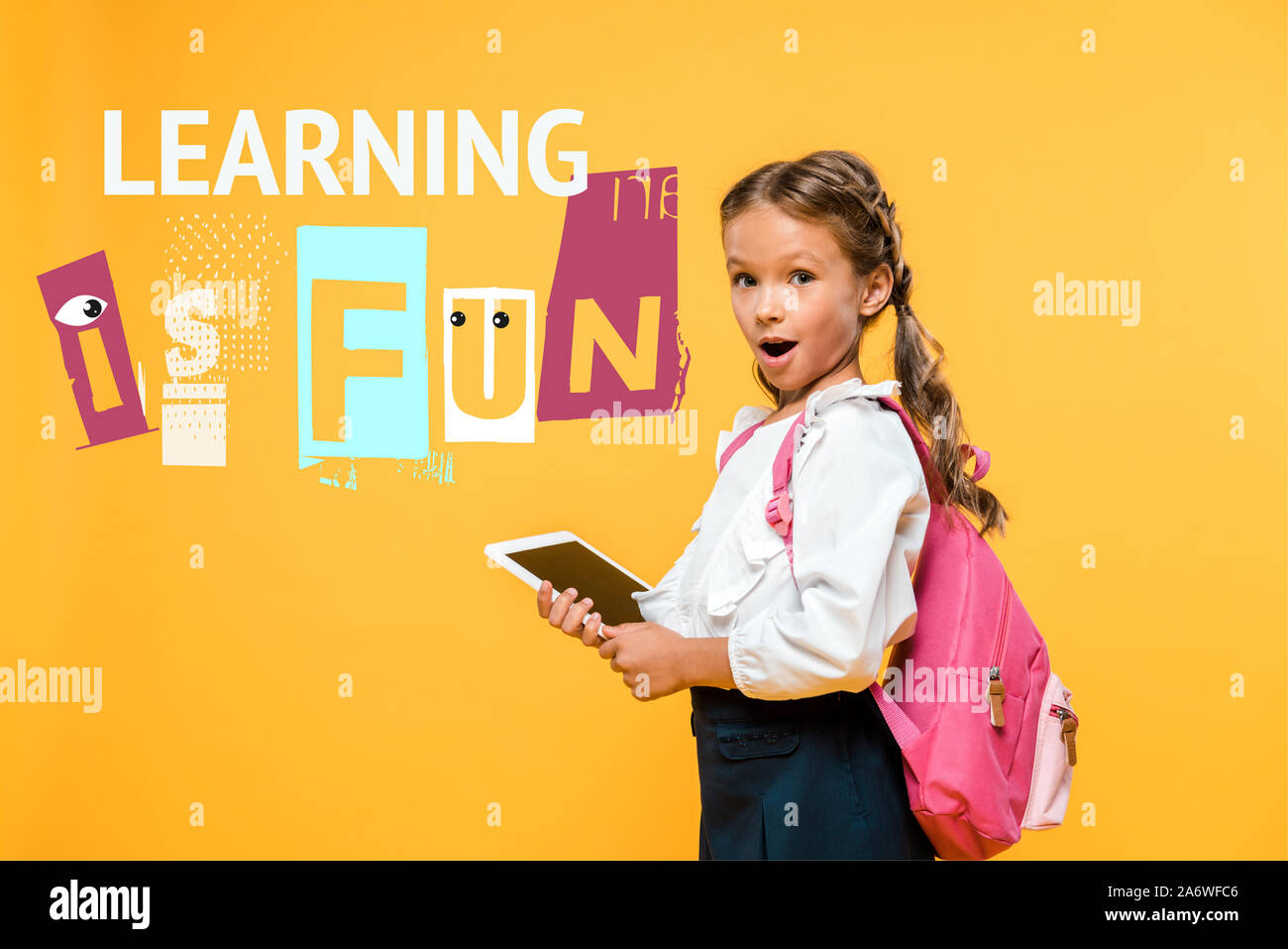 Überrascht schoolkid Holding digitale Tablette mit leeren Bildschirm in der Nähe von Lernen in der Spaß-Schriftzüge auf Orange Stockfoto