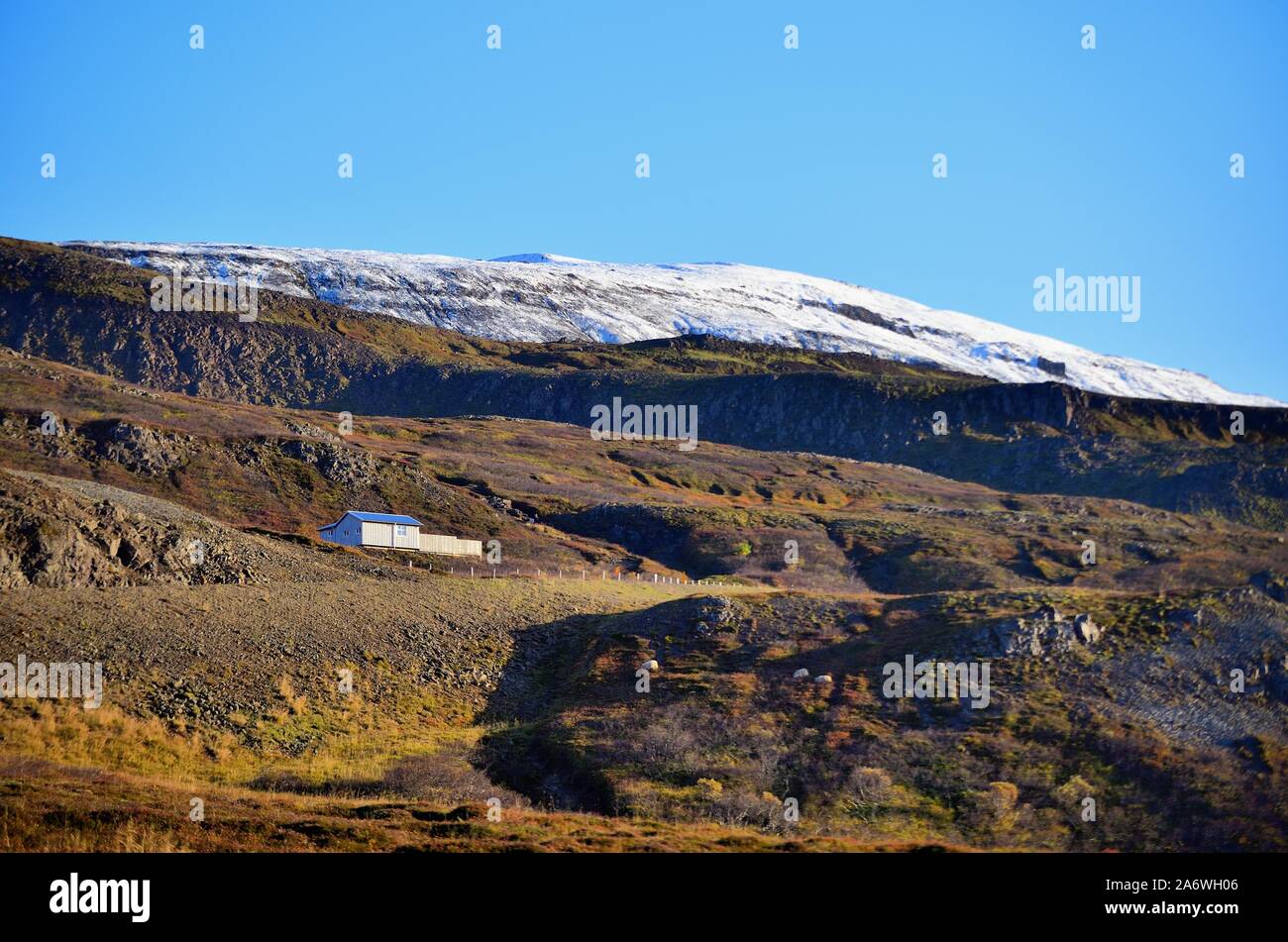 Bezirk Hróarstunga, Island. Ein Haus, eingebettet in den Bergen über Unaos (' der Mündung des Uni"). Schöne Aussichten im Überfluss in der Gegend. Stockfoto