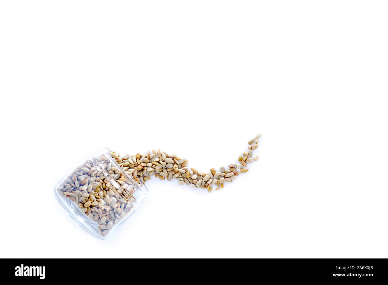 Organische geröstete Sonnenblumenkerne kein Salz Verschütten von Jar auf weißem Hintergrund. Flach Zusammensetzung im Querformat mit Platz für Text. Gesund Stockfoto