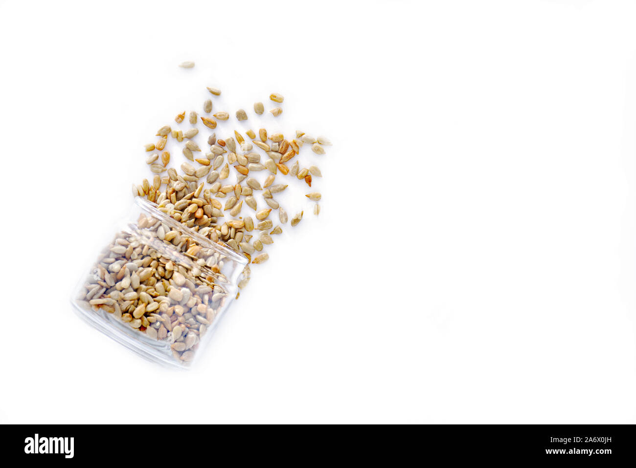 Organische geröstete Sonnenblumenkerne kein Salz Verschütten von Jar auf weißem Hintergrund. Flach Zusammensetzung im Querformat mit Platz für Text. Gesund Stockfoto