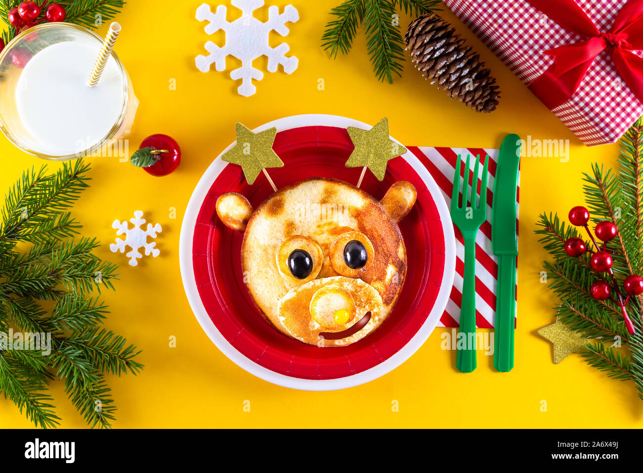Das kreative Weihnachten Kind essen Kunst essbare Hirsche auf rote Platte mit Sterne statt Hörner als xmas Frühstück. Art, niedliche Rehe aus Pfannkuchen und Beeren. Stockfoto