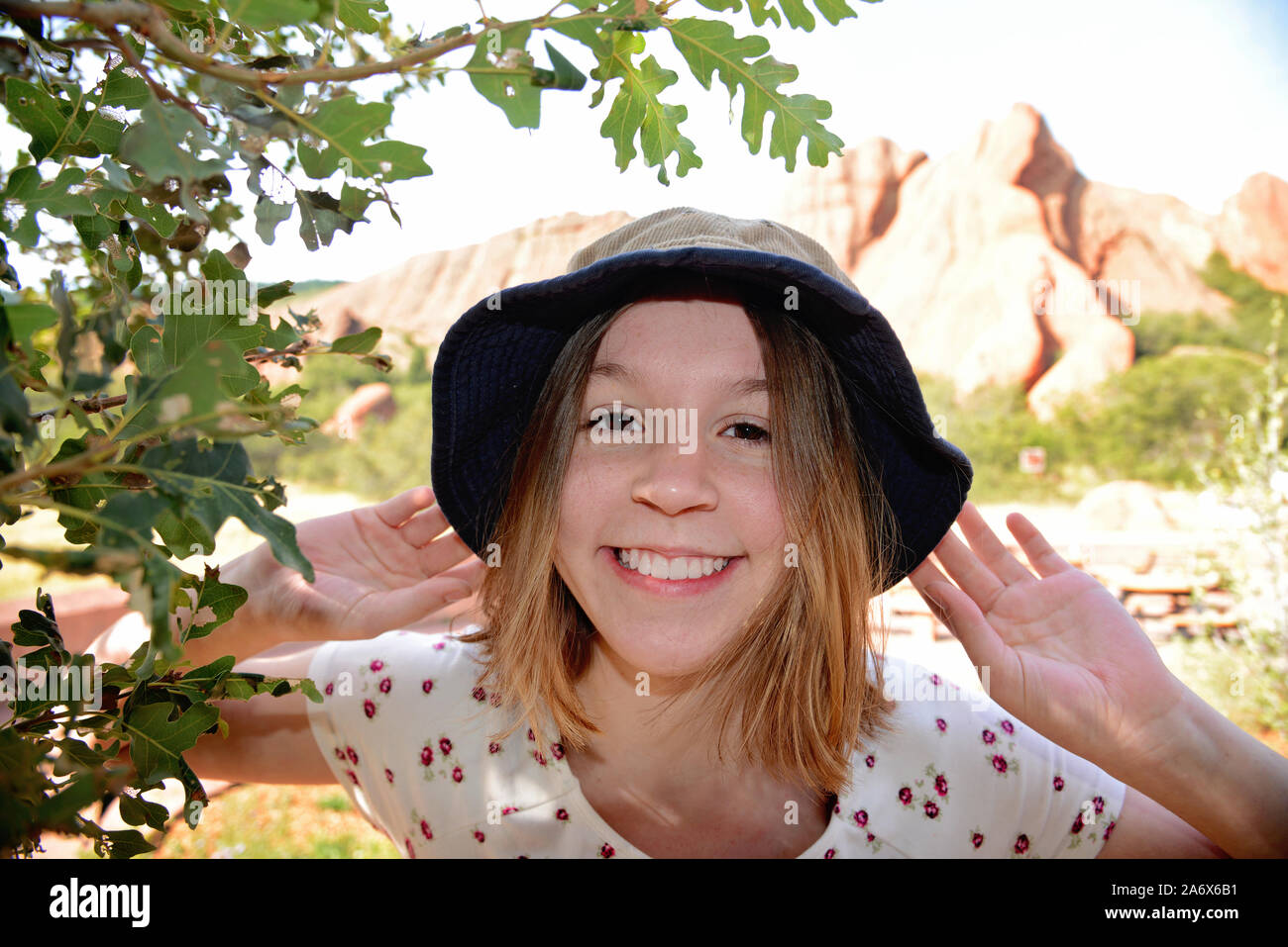 Nahaufnahme der teenage Mädchen lächelnd tragen Hut mit felsigen outcroppings im Hintergrund Landschaft Stockfoto