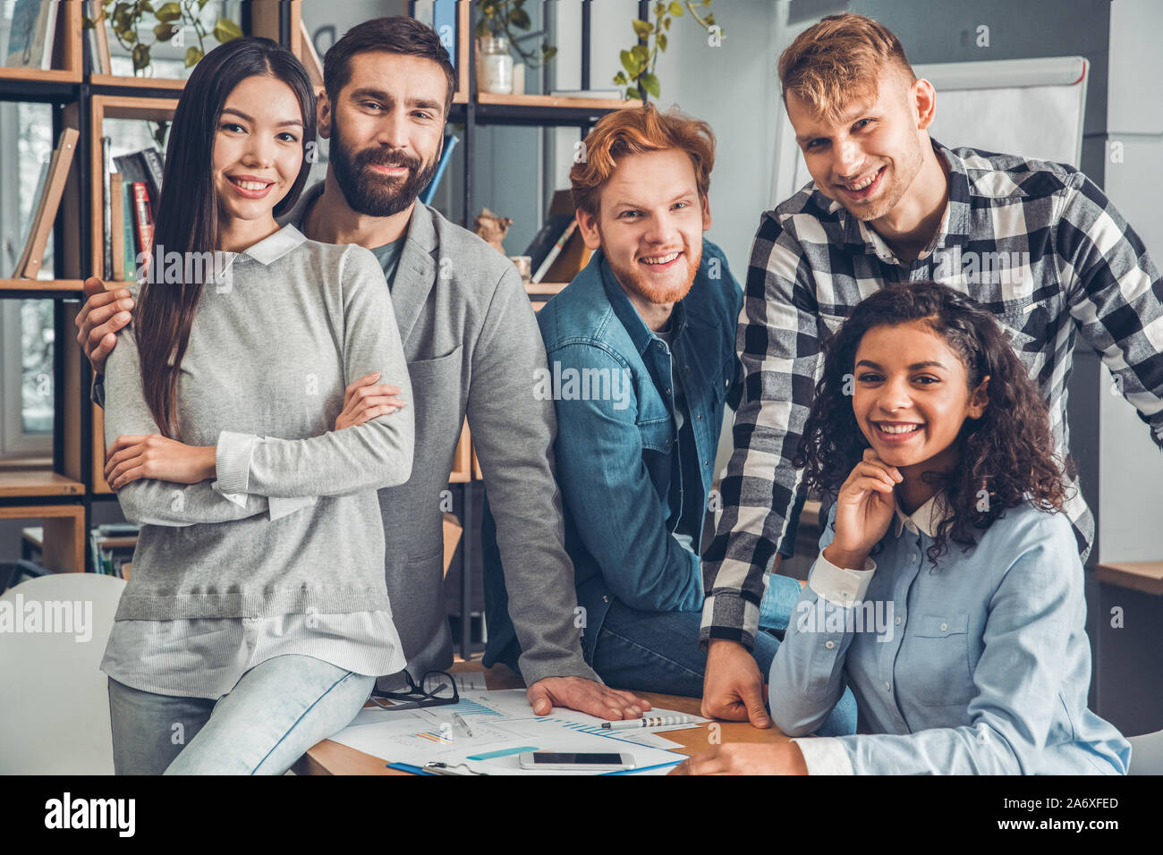 Startupers zusammen arbeiten im Büro umarmen suchen Kamera freudige Stockfoto