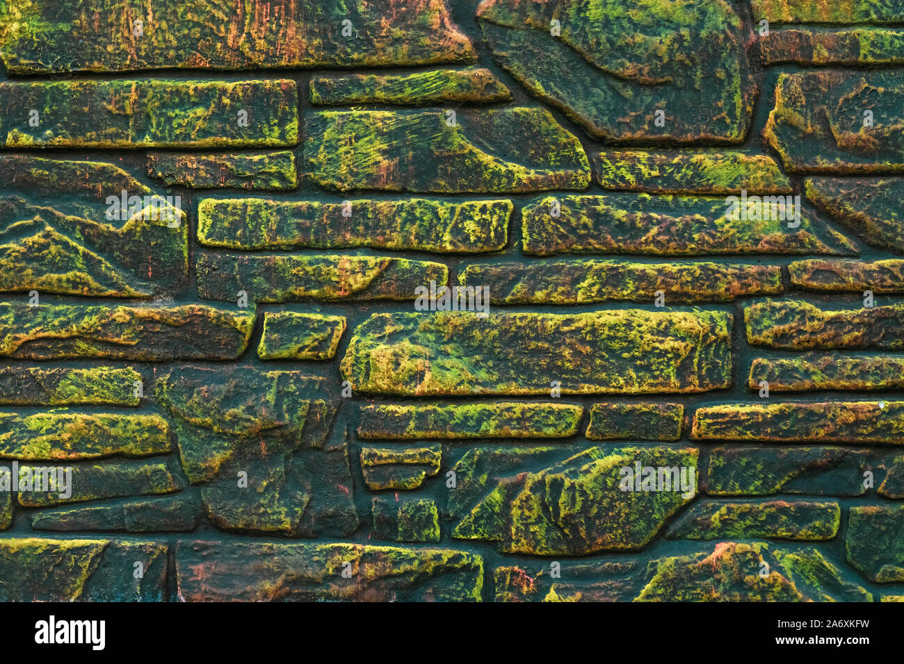 Fleckige bemalte Mauer aus Stein. Fluoreszierende Farbe auf Rock Hintergrund. Grüne und gelbe Textur im modernen Stil. Brick Wall Hintergründe. Abstrakte Muster. Stockfoto