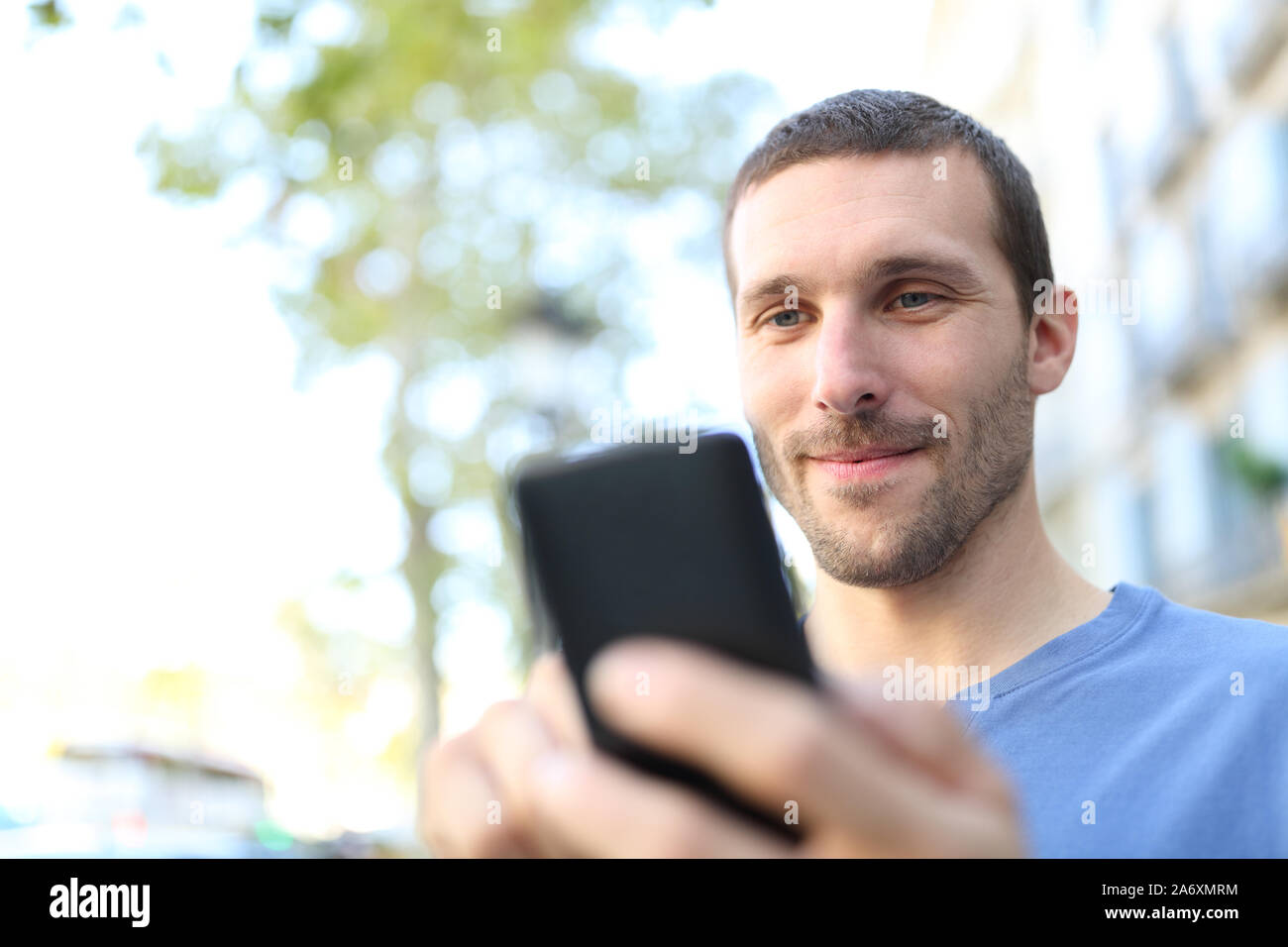 Nahaufnahme eines zufriedenen Menschen mittels Smart Phone zu Fuß auf der Straße Stockfoto