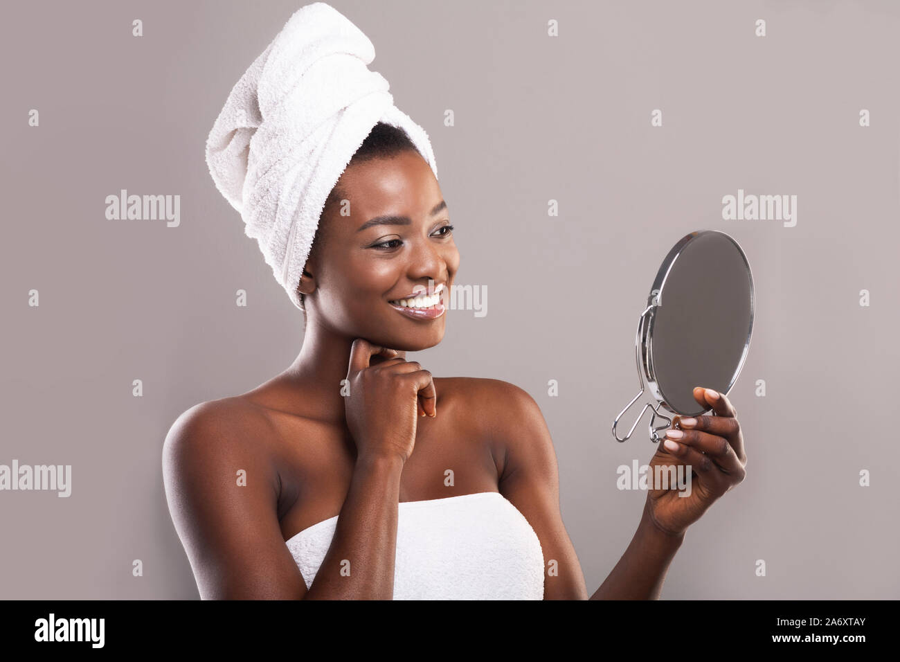 Attraktive schwarze Frau mit Spiegel und betrachten ihre perfekte Haut Stockfoto