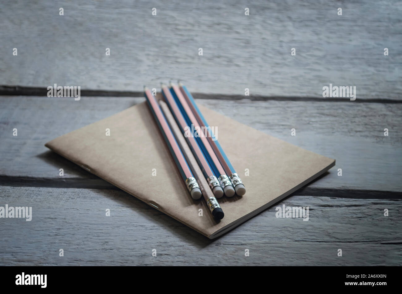 Konzept der Bleistift mit einem schwarzen Radiergummi auf einem braunen Hinweis Buch platziert und auf Holz Tisch Vintage Style Stockfoto