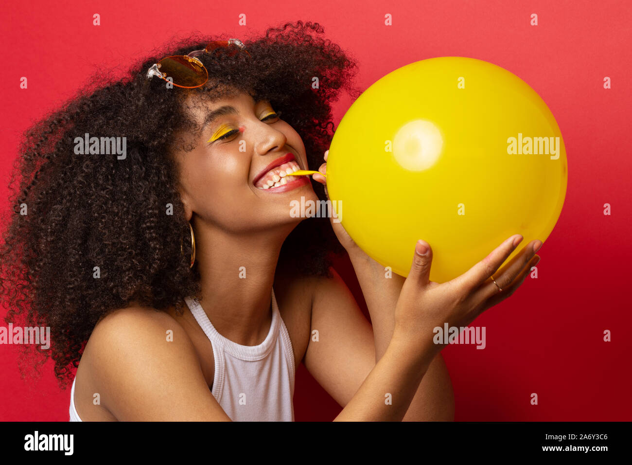 Mulatte Modell pumpt einen gelben Ballon Stockfoto
