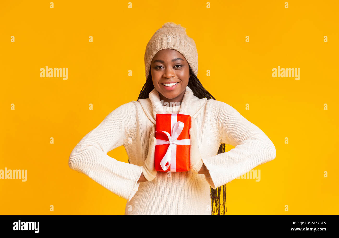 Lächelnd afro girl Holding neue Jahr Geschenk neben Brust Stockfoto