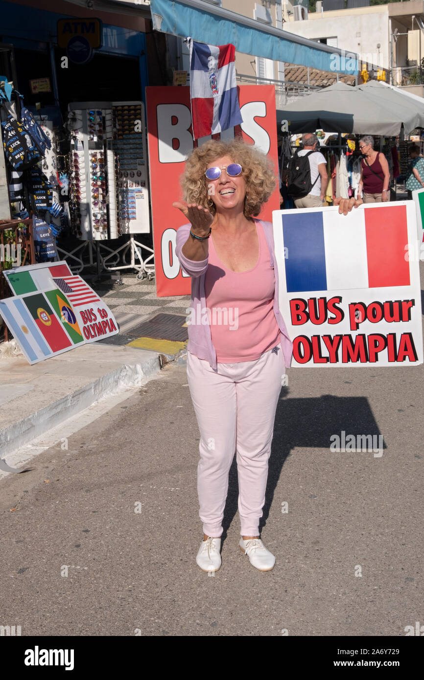 Ein Lächeln glücklich griechische Frau in Katakolon wirbt Bus Fahrten für Touristen zu den nahe gelegenen Olympia und den Olymp. Griechenland, 2019. Stockfoto