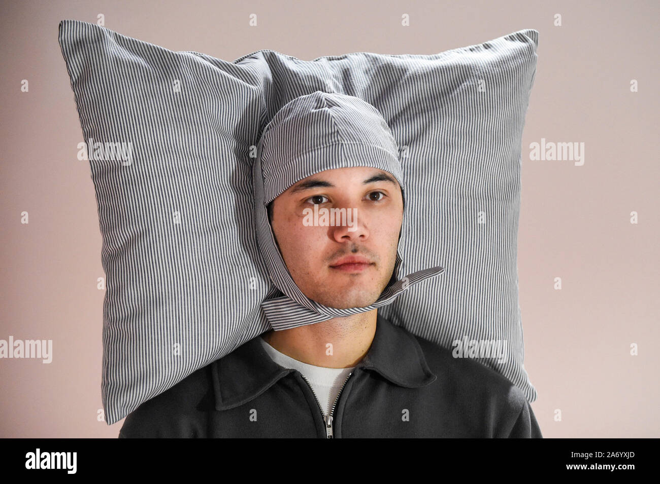 London, Großbritannien. 29. Oktober 2019. Ein Mitarbeiter trägt 'Pillowig', 2005, von JooYoun Paek, ein Design, um Benutzern zu ermöglichen, überall zu schlafen. Vorschau von "24/7: ein Weckruf für unsere Non-Stop-Welt", eine neue Ausstellung eröffnet am 31. Oktober im Somerset House. Die show untersucht unsere Unfähigkeit, aus unseren Rund-um-die-Kultur zu wechseln. Über 50 multi-disziplinäre funktioniert der Druck zu produzieren und Informationen rund um die Uhr konsumieren erkunden. die Besucher auf einem 24-Stunden-Rhythmus von Dämmerung zu Dämmerung durch interaktive Installationen. Credit: Stephen Chung/Alamy leben Nachrichten Stockfoto