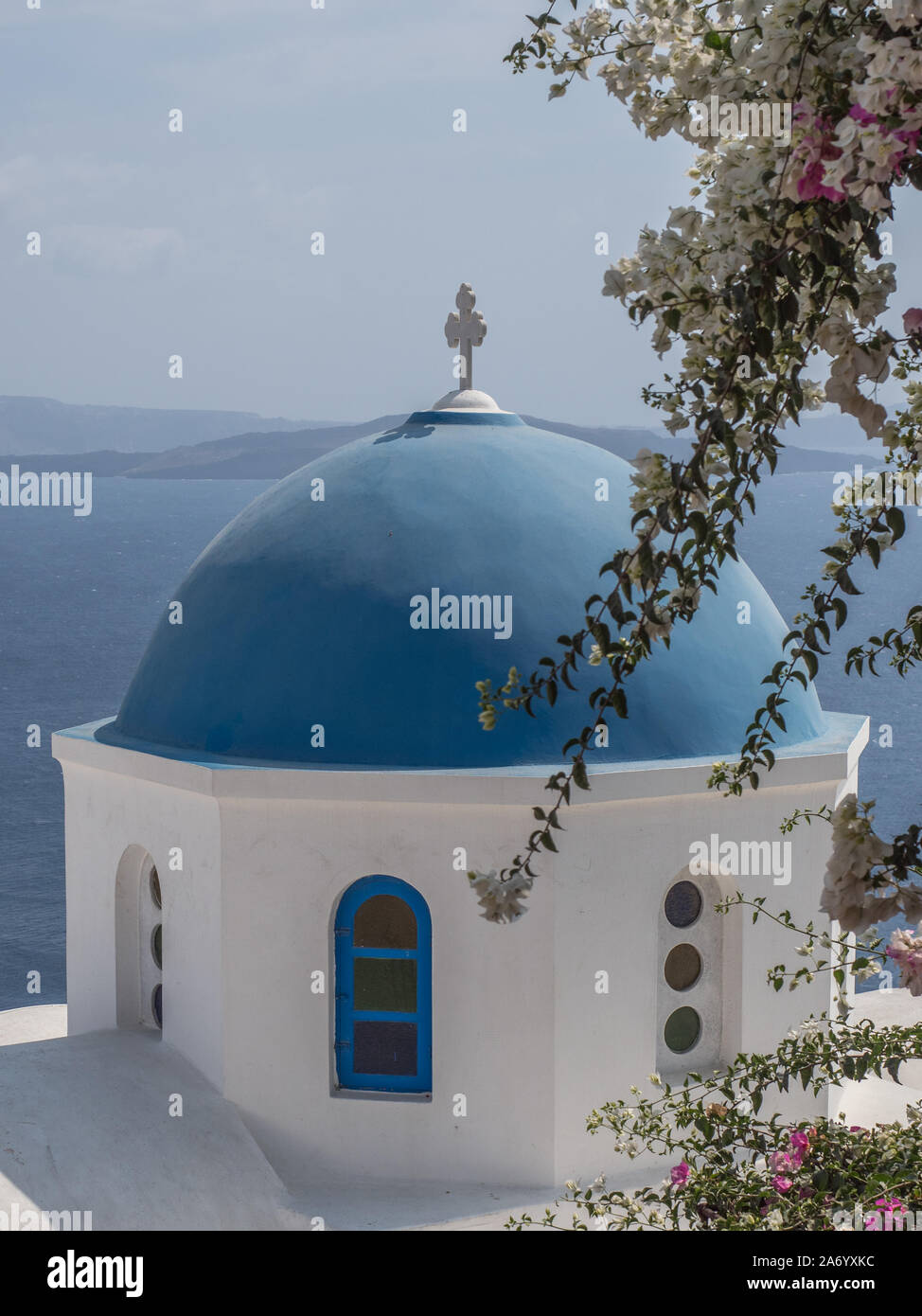Eine Nahaufnahme des berühmten blauen Kuppel Kirche Kapelle Dach mit Kreuz Kruzifix auf die Oberseite mit Meer berge Hintergrund Oia Santorini Stockfoto