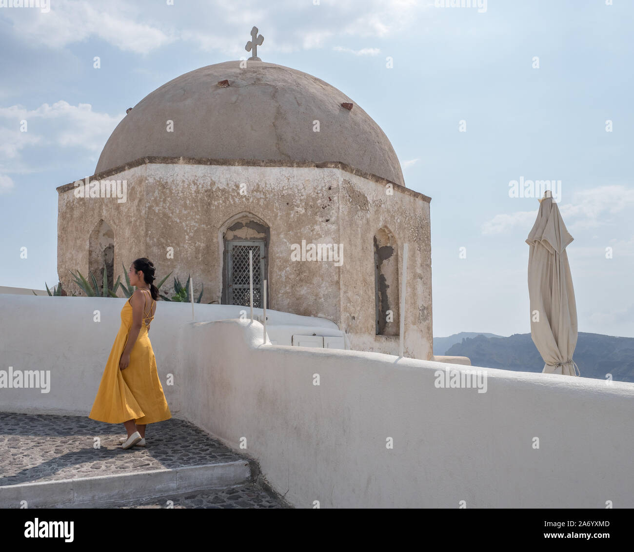 Ein Profil der junge schlanke Asiatin Profil steht die weiße Wand Kirche Kapelle unter blauem Himmel mit Wolken Reiseziel Oia Santorini Stockfoto