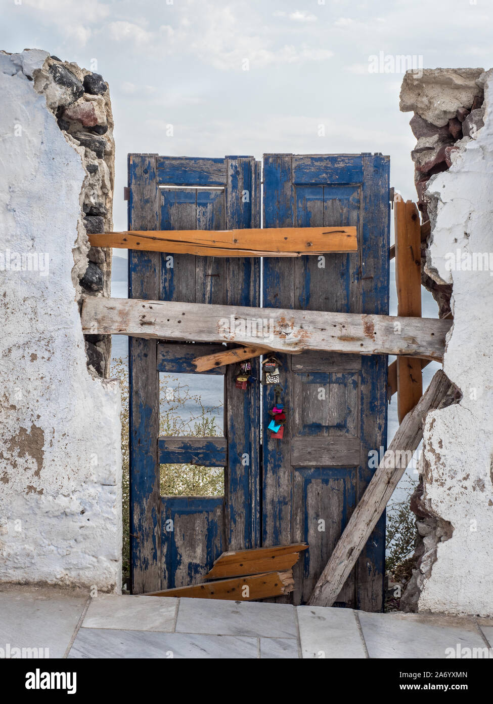 Ein verfallenes alte verwitterte maroden Tür in Tür weg Holz abblätternde Farbe gehalten von Nagelte Bretter, zerbröckelnden Beton weiße Wand Oia Stockfoto