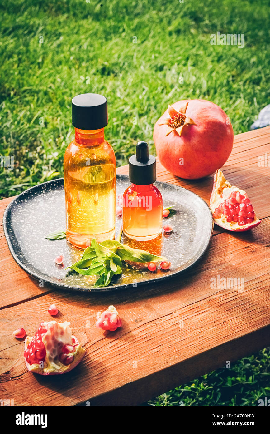 Trendy Sonnenlicht Granatapfel Kernöl, Molke in verschiedenen Flaschen auf Holz- Hintergrund. Konzept der Anti-aging Bio care Stockfoto