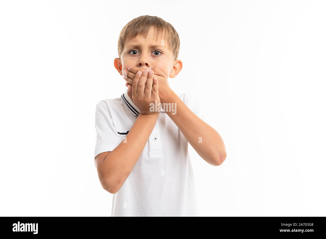 Schüler auf einem weißen Hintergrund schließt seinen Mund mit den Händen, ist Angst heraus herauszuplatzen, emotionale Portrait Stockfoto