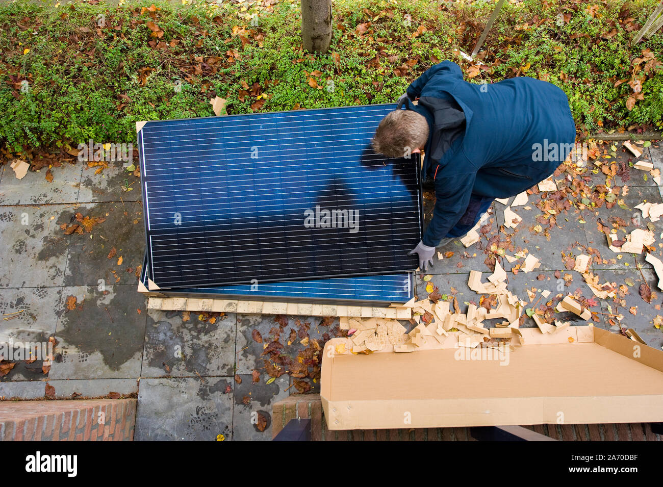 Ein Arbeitnehmer ist Abholung Solarzellen auf einem Dach in den Niederlanden zu installieren. Stockfoto