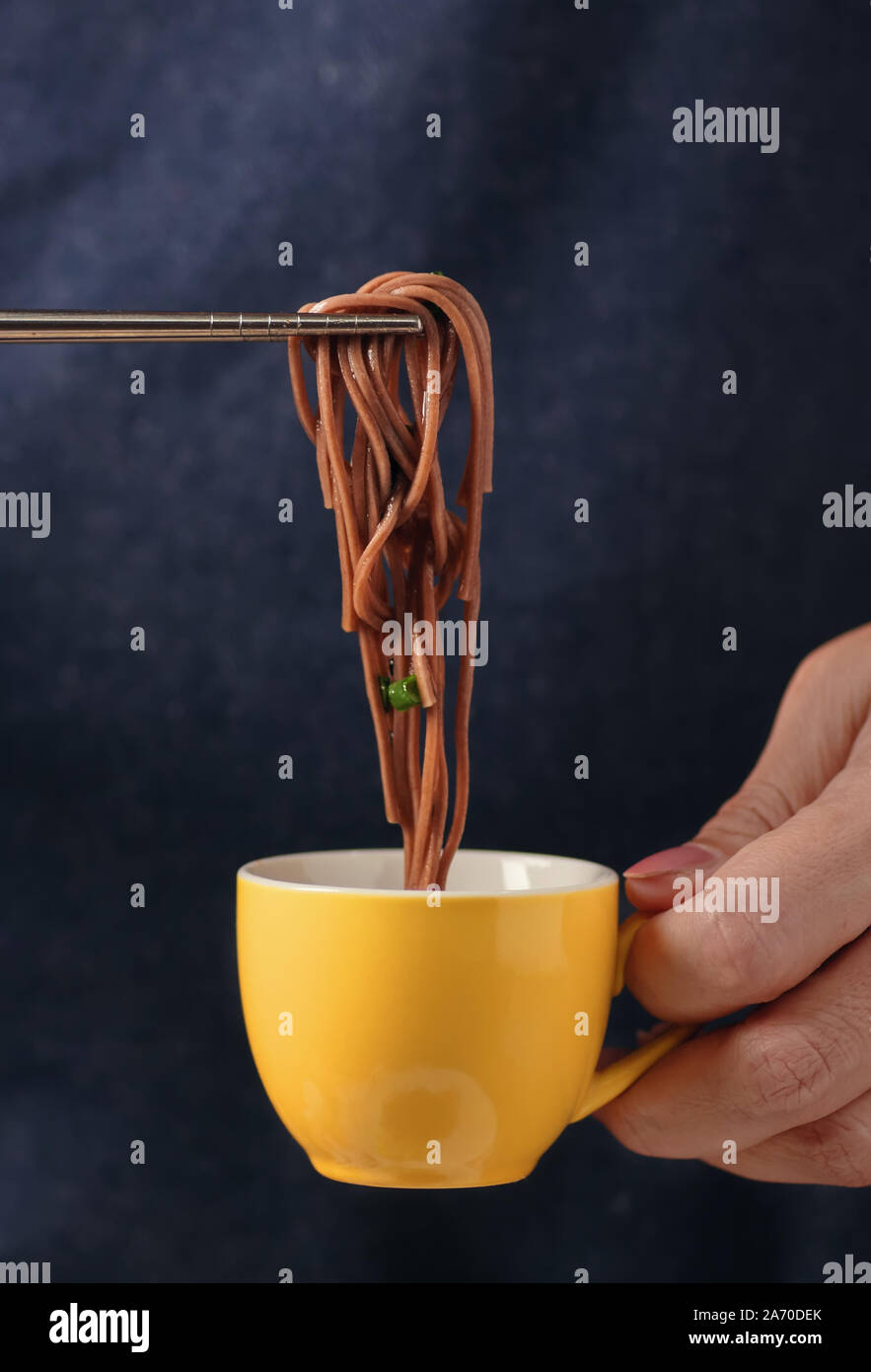 Der buchweizen Nudeln von einer Tasse Soße von Stäbchen Pick Stockfoto