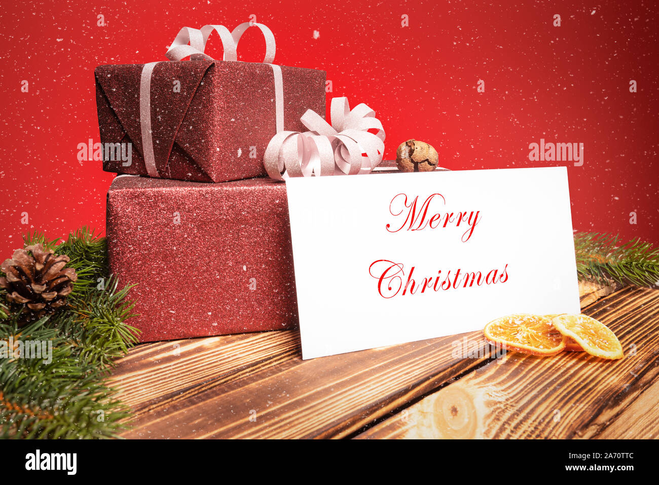 Zwei Weihnachtsgeschenke liegen auf einem Holztisch mit einer Grußkarte Stockfoto
