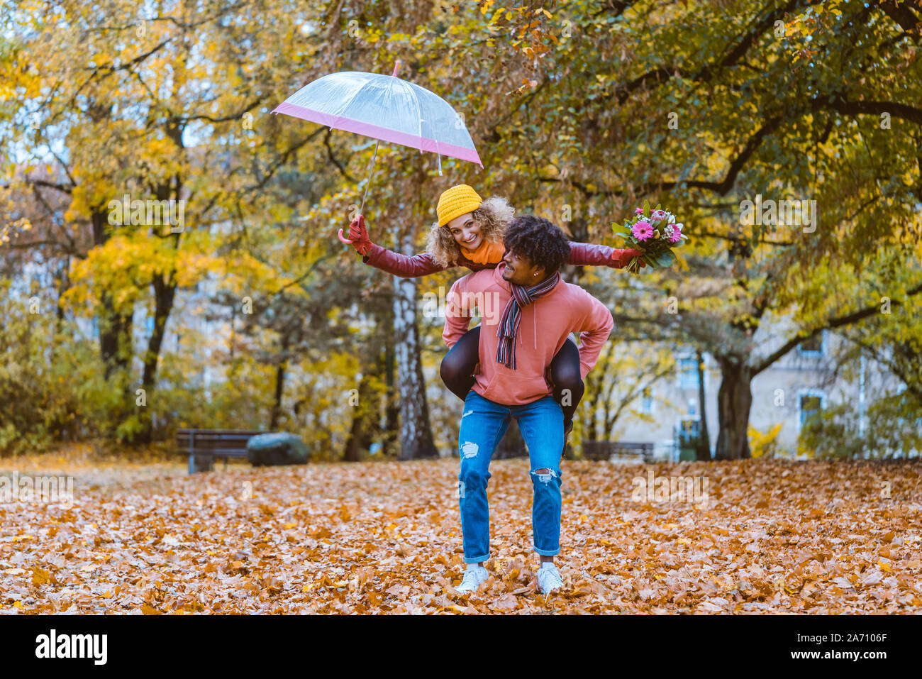 Schwarzer Mann, der seine kaukasische Mädchen huckepack im Herbst Stockfoto