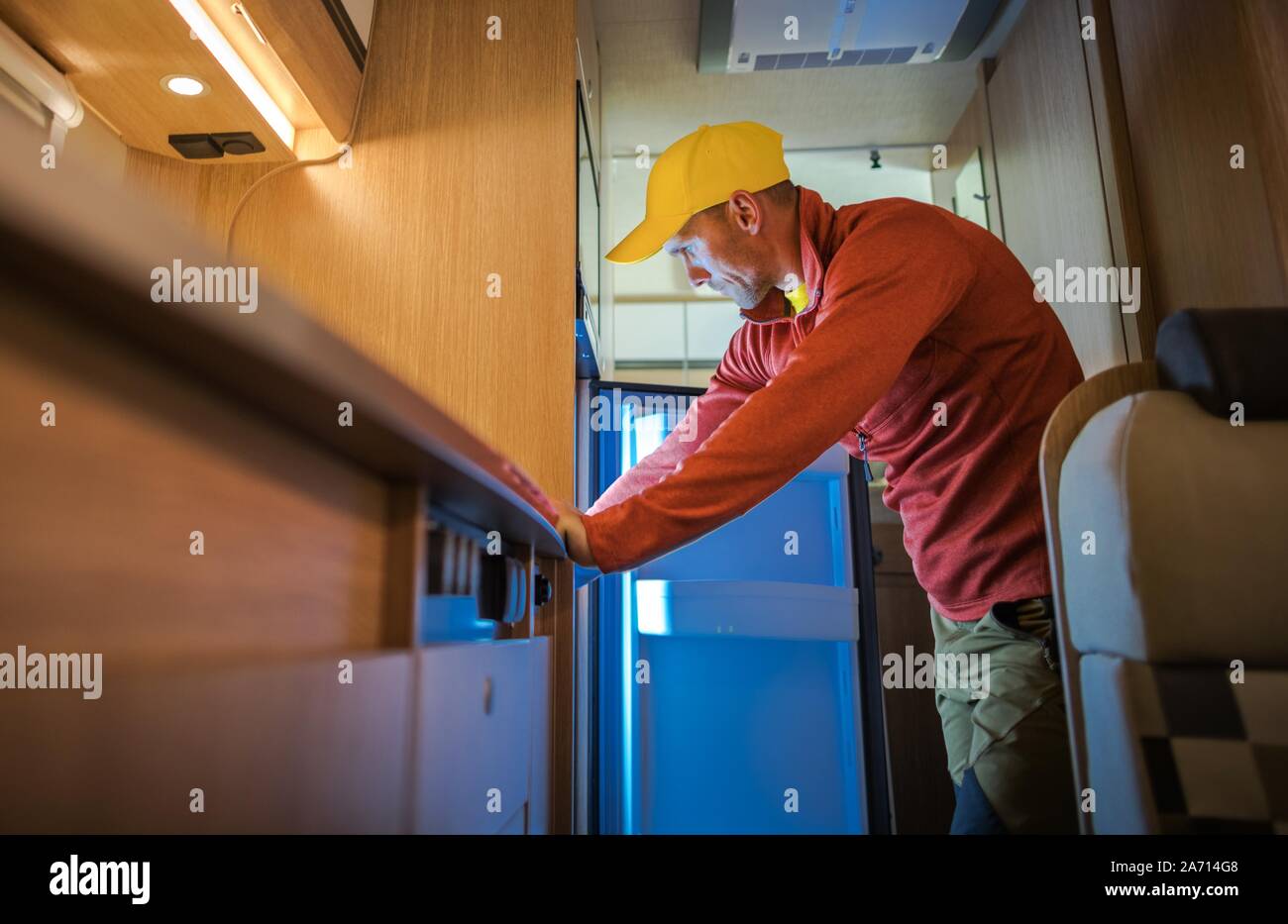 Kaukasischen Männern in seinem 30s auf der Suche nach Innen RV Wohnmobil Kühlschrank. Reisemobil Appliances. Stockfoto