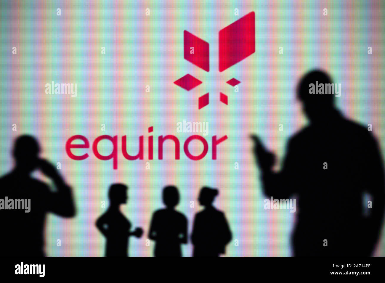 Die Equinor Logo ist auf einen LED-Bildschirm im Hintergrund, während eine Silhouette Person ein Smartphone verwendet (nur redaktionelle Nutzung) Stockfoto