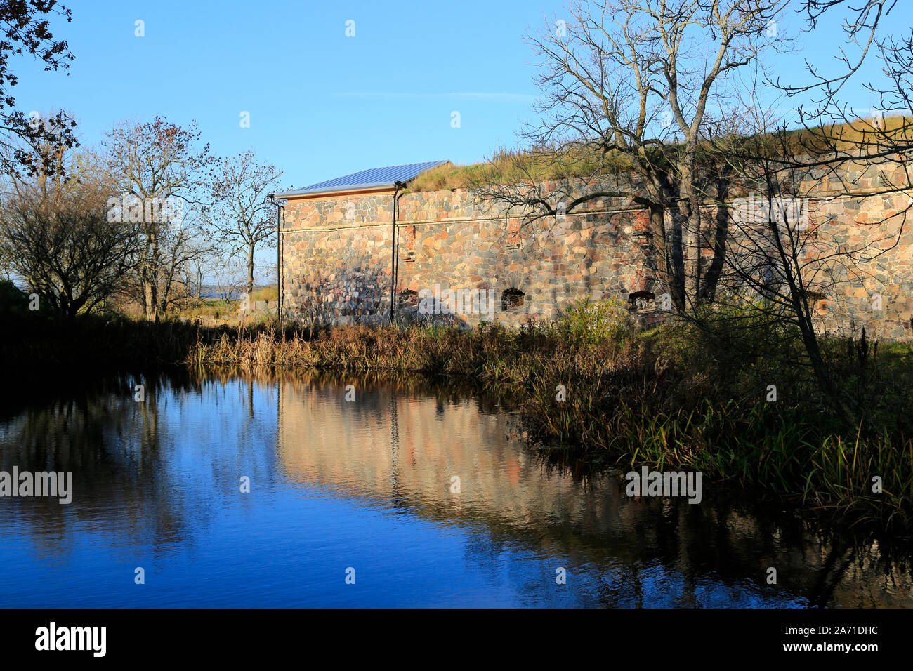 Kleiner Teich mit Reflexionen auf den blauen Himmel und Befestigungsanlagen in Piper's Park, Suomenlinna, die zum UNESCO-Weltkulturerbe in Helsinki, Finnland. Okt 2019 Stockfoto