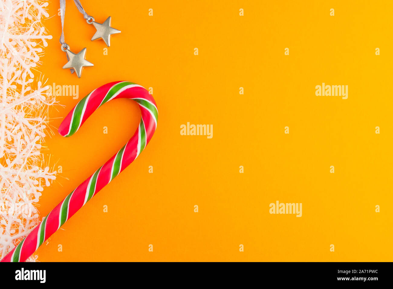 Traditionelle Weihnachten caramel Candy Cane und Schneeflocken auf einem orangefarbenen Hintergrund. Winterurlaub festliche Grußkarte mit Platz für den Text kopieren Stockfoto