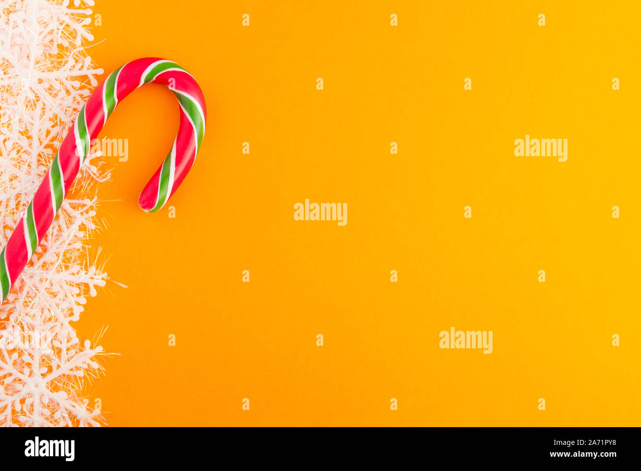 Traditionelle Weihnachten caramel Candy Cane und Schneeflocken auf einem orangefarbenen Hintergrund. Winterurlaub festliche Grußkarte mit Platz für den Text kopieren Stockfoto