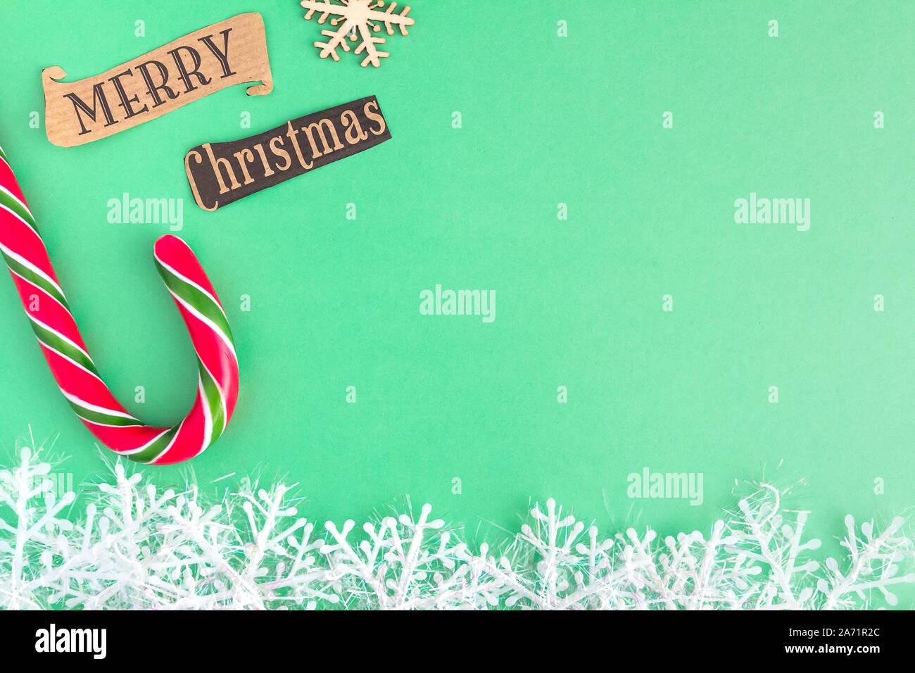 Traditionelle Weihnachten caramel Candy Cane und Schneeflocken auf einem Mint Grüner Hintergrund mit Frohe Weihnachten Schriftzug. Winterurlaub festliche Begrüßung Stockfoto