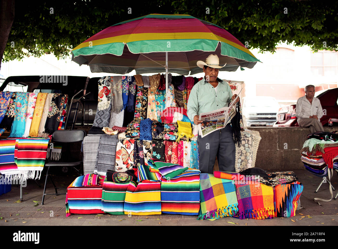 Mexikanische Anbieter lesen Zeitung an seinem Marktstand verkaufen bunte Textilien im Mercado Hidalgo. Guanajuato, Mexiko. Jun 2019 Stockfoto