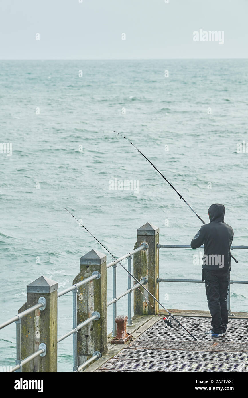 Ein Fischer auf dem Deck am Pier von Bournemouth, England, an einem kalten, windigen Tag. Stockfoto