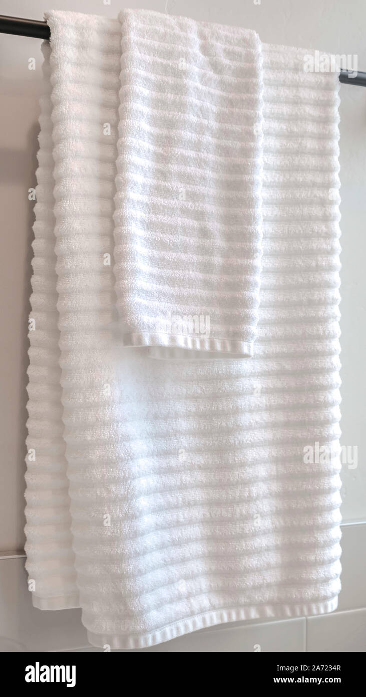 Vertikale weiße Handtücher hängen an einem Handtuchhalter Stockfoto