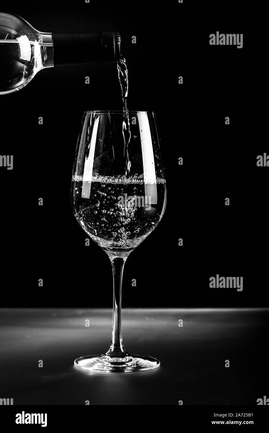 Flasche und ein Glas Weisswein auf schwarzem Hintergrund. Stockfoto