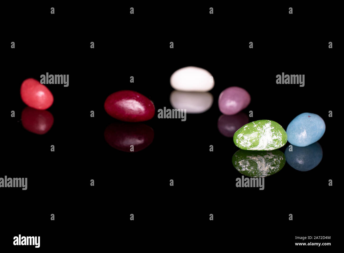 Gruppe von sechs ganze jelly bean Candy auf schwarzem Glas isoliert Stockfoto