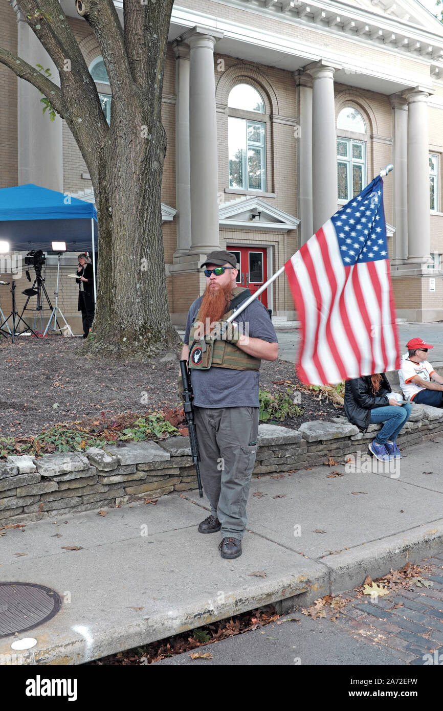 Stolz American Holding US Flag und Gewehr auf eine politische Kundgebung auf dem Otterbein Universitätscampus in Westerville, Ohio, USA. Stockfoto