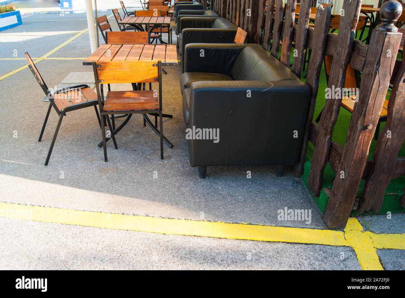 Outdoor Recreation Area - Tische und Stühle aus Holz und Leder Stühle gegen einen Holzzaun. Stockfoto