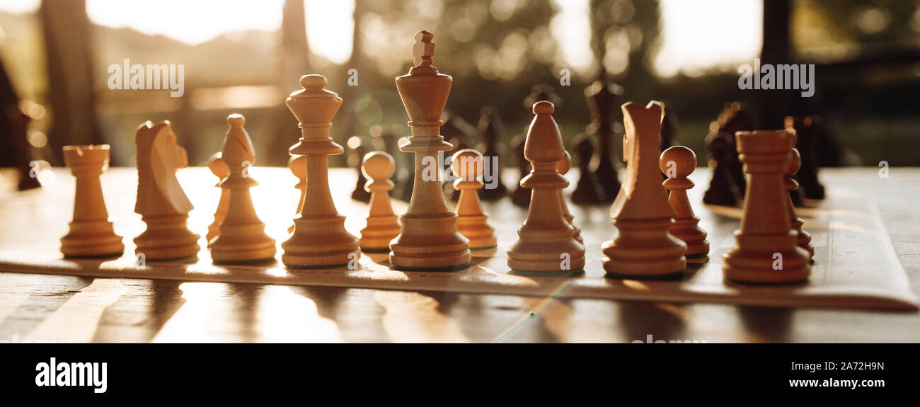 Schach Spielen auf einem Schachbrett bei Sonnenuntergang. Taktik und Strategie. Schwarze und weiße Zahlen. Stockfoto