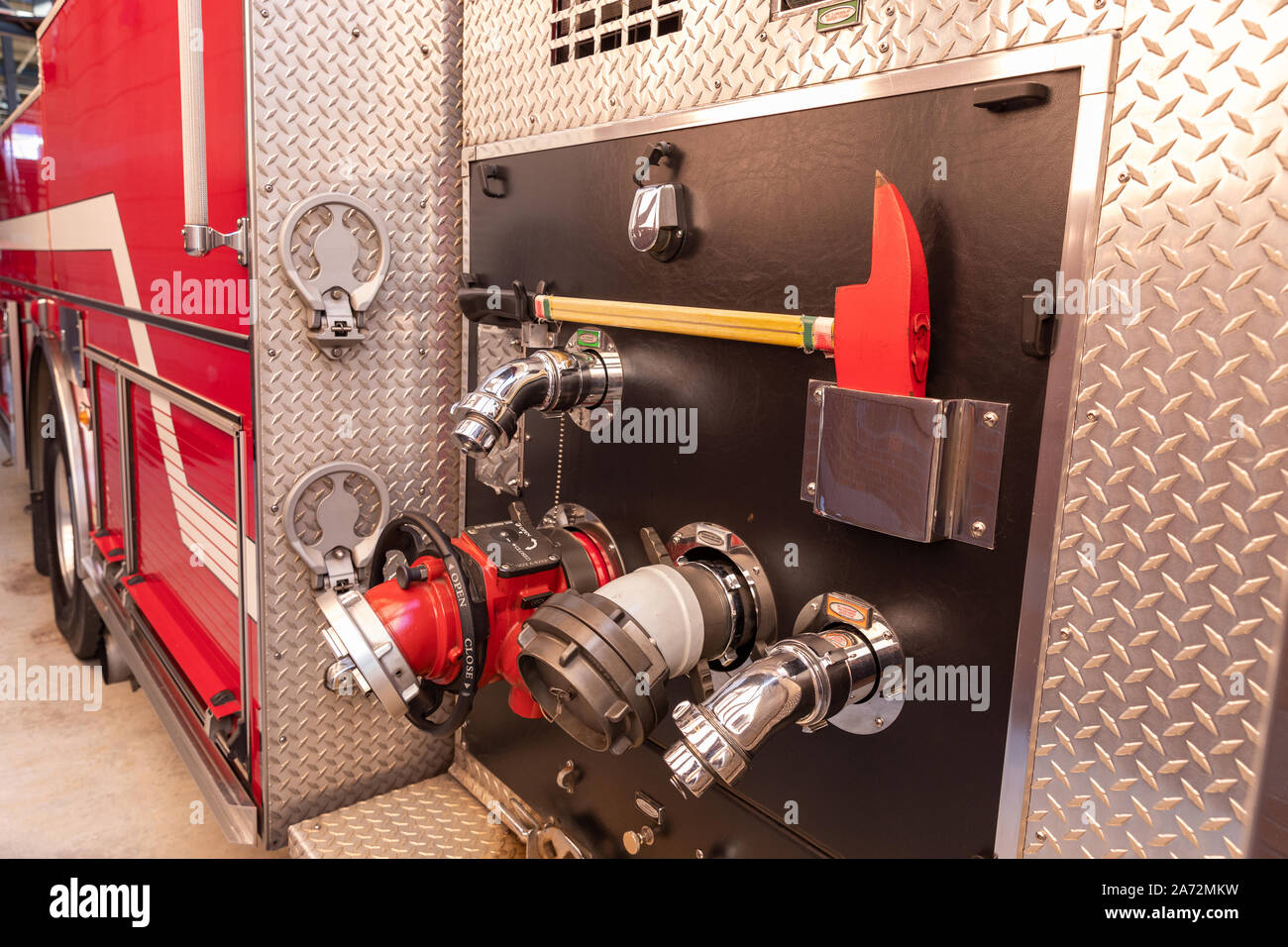 Seite der roten Feuerwehrauto mit Schlauchanschlüssen und Ax Stockfoto