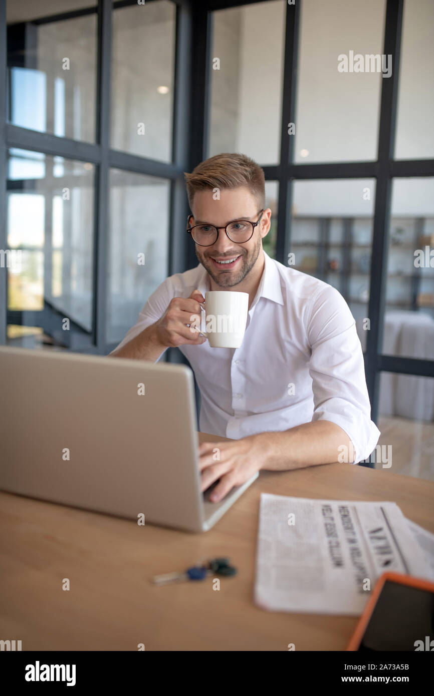 Geschäftsmann Kaffee trinken und Abrufen der E-Mails auf Notebook Stockfoto
