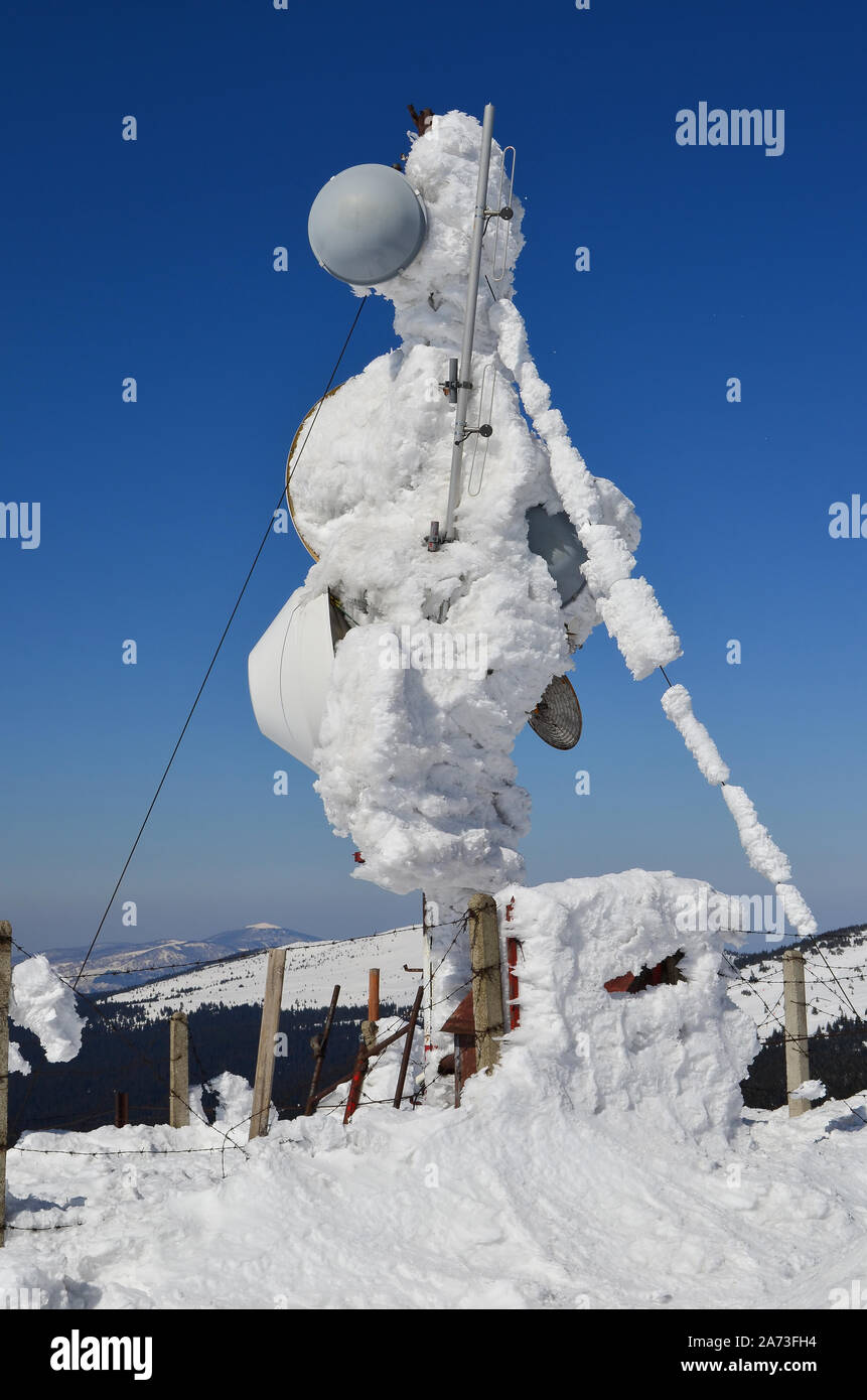 Antenne für mehrere Zwecke, gefroren und mit Schnee bedeckt, die durch beschädigte Stacheldraht eingezäunt Stockfoto