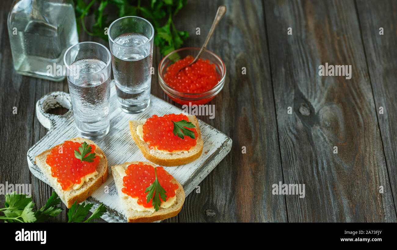 Wodka mit Lachskaviar und Brot Toast auf Holz- Hintergrund. Alkohol reines Handwerk Drink und traditionellen Snacks. Negativer Platz. Feiern, Essen und lecker. Ansicht von oben. Stockfoto