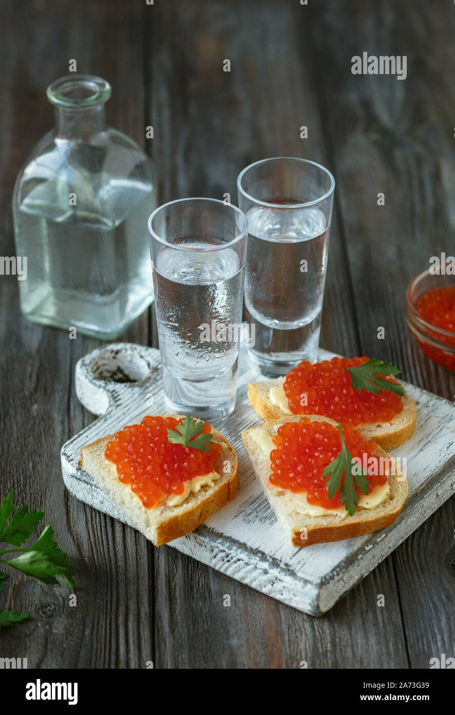 Wodka mit Lachskaviar und Brot Toast auf Holz- Hintergrund. Alkohol reines Handwerk Drink und traditionellen Snacks. Negativer Platz. Feiern, Essen und lecker. Ansicht von oben. Stockfoto