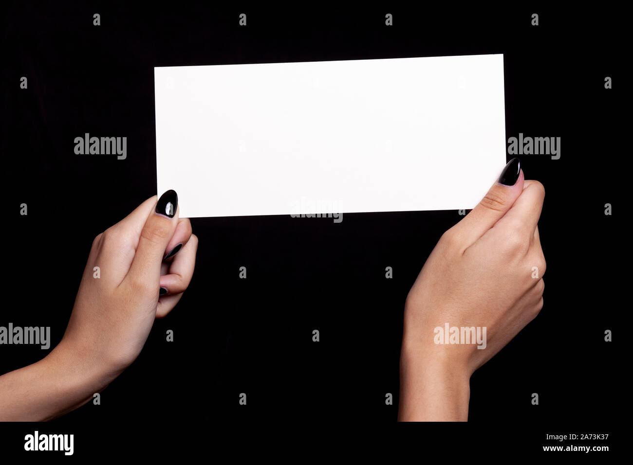 Hände halten weiße Karte auf schwarzem Hintergrund - Copyspace Stockfoto