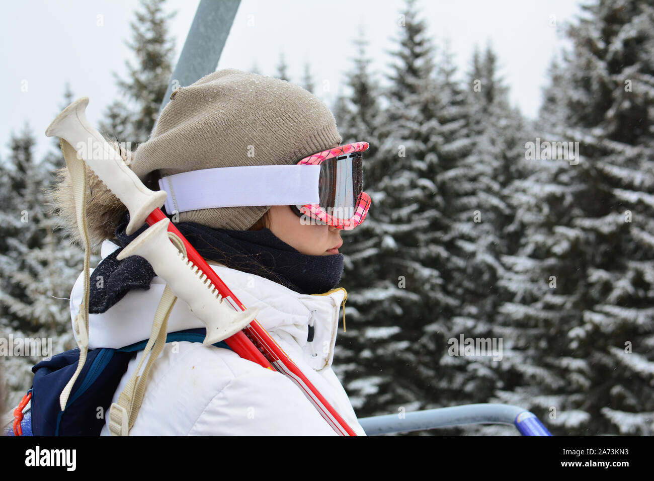 Junge, hübsche Mädchen in weißen Skianzug, mit grauer Kappe, googgles und Skistöcke mit Seilbahn, Skigebiet Kopaonik, Serbien Stockfoto