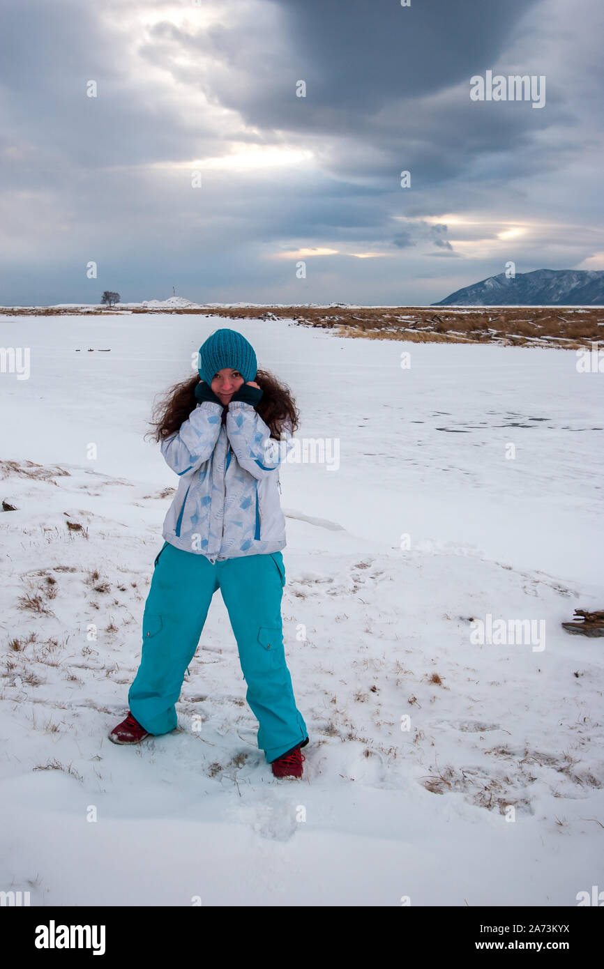 Ein Madchen Mit Langen Haaren Im Winter Kleidung Steht Auf Dem Schnee Am Ufer Eines Gefrorenen Fluss Im Winter Und Zieht Ein Hut Mit Ihren Handen Vertikale Rahmen Werden Stockfotografie Alamy