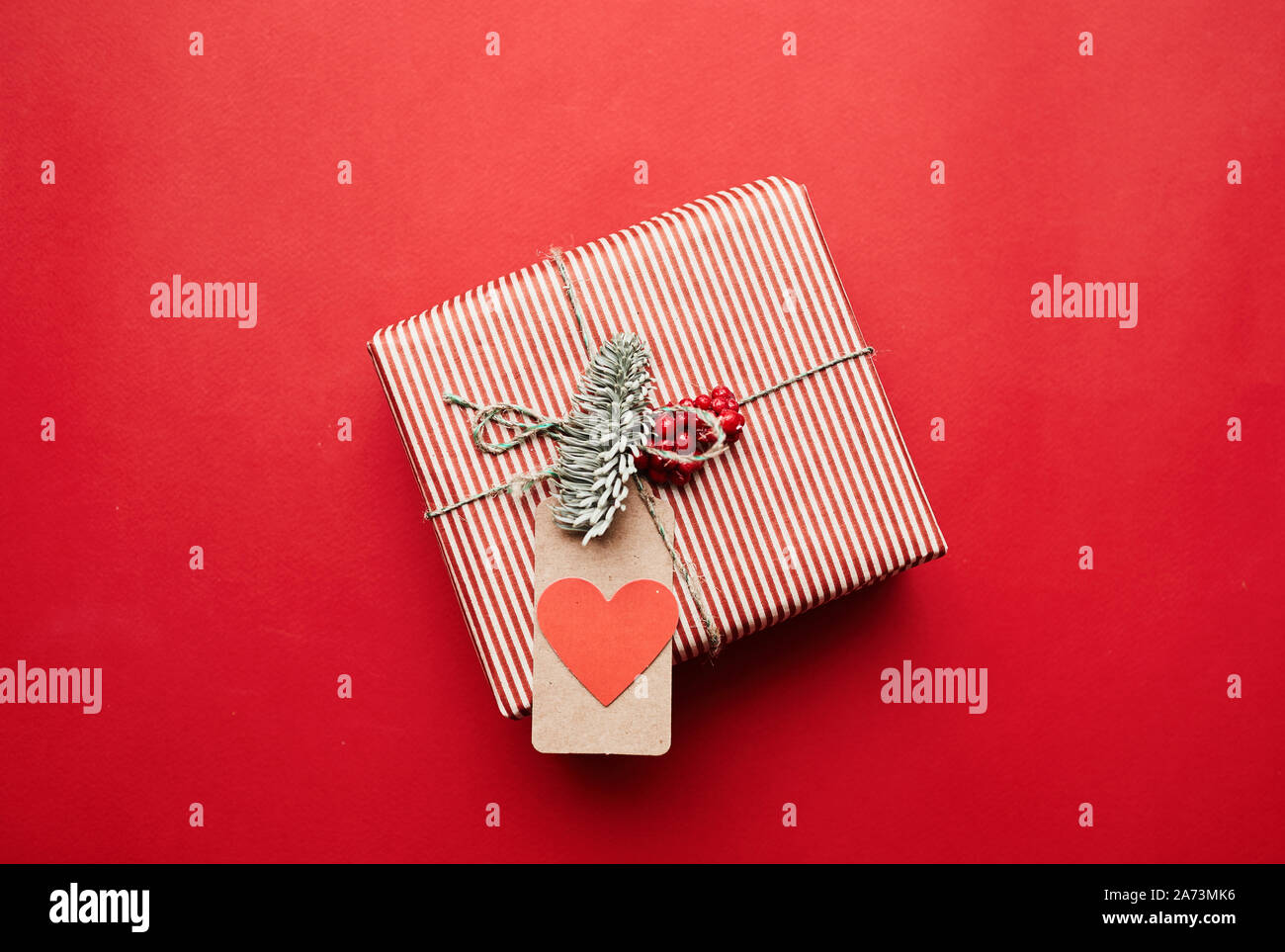Bild von Geschenkbox in Geschenkpapier mit Grußkarte auf sie isoliert auf rotem Hintergrund Stockfoto